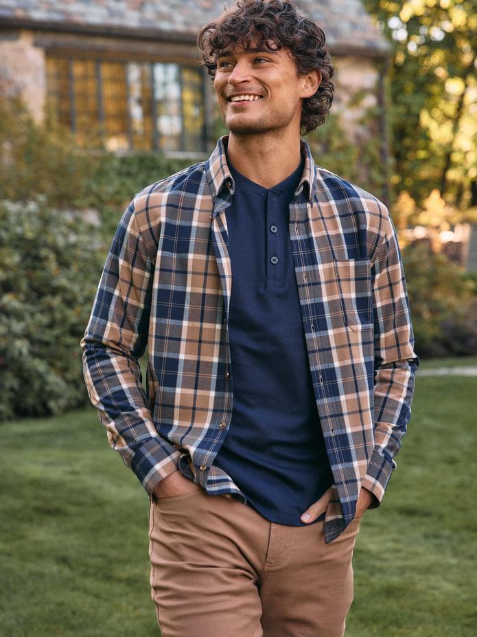 Smiling man in an open plaid flannel over a navy henley with khaki pants