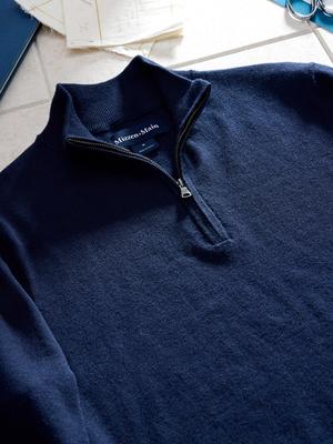 A close-up flat-lay shot of the collar and zipper of a navy blue quarter-zip sweater showing the Mizzen+Main neck tag.