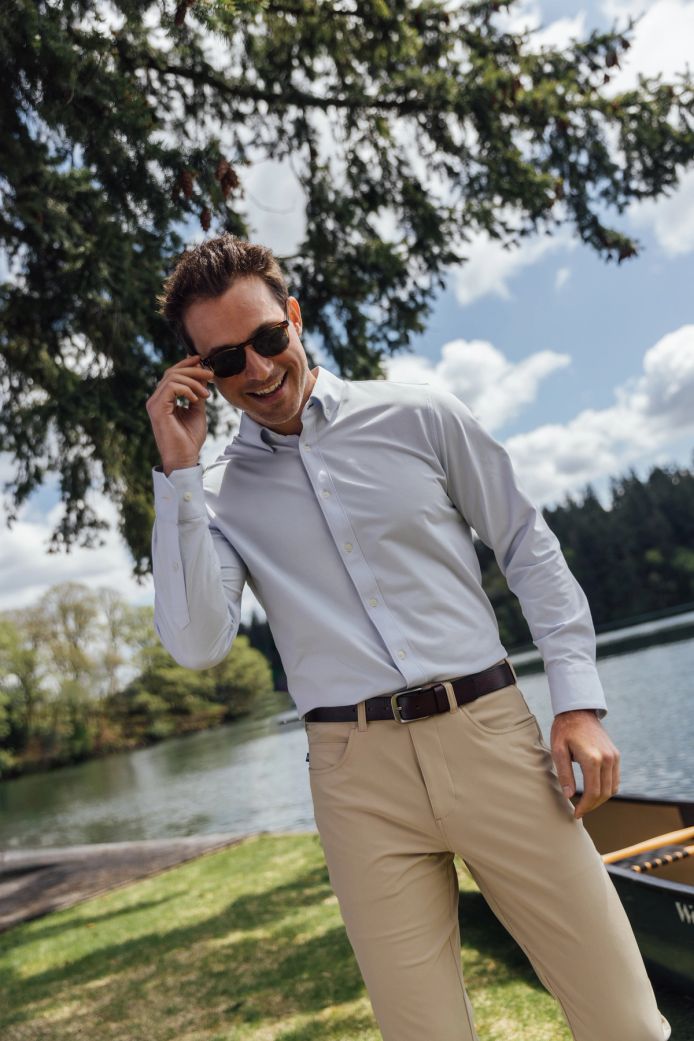 A man dressed in a shirt and khaki pants stands next to a canoe, preparing for a day of exploration on the lake.