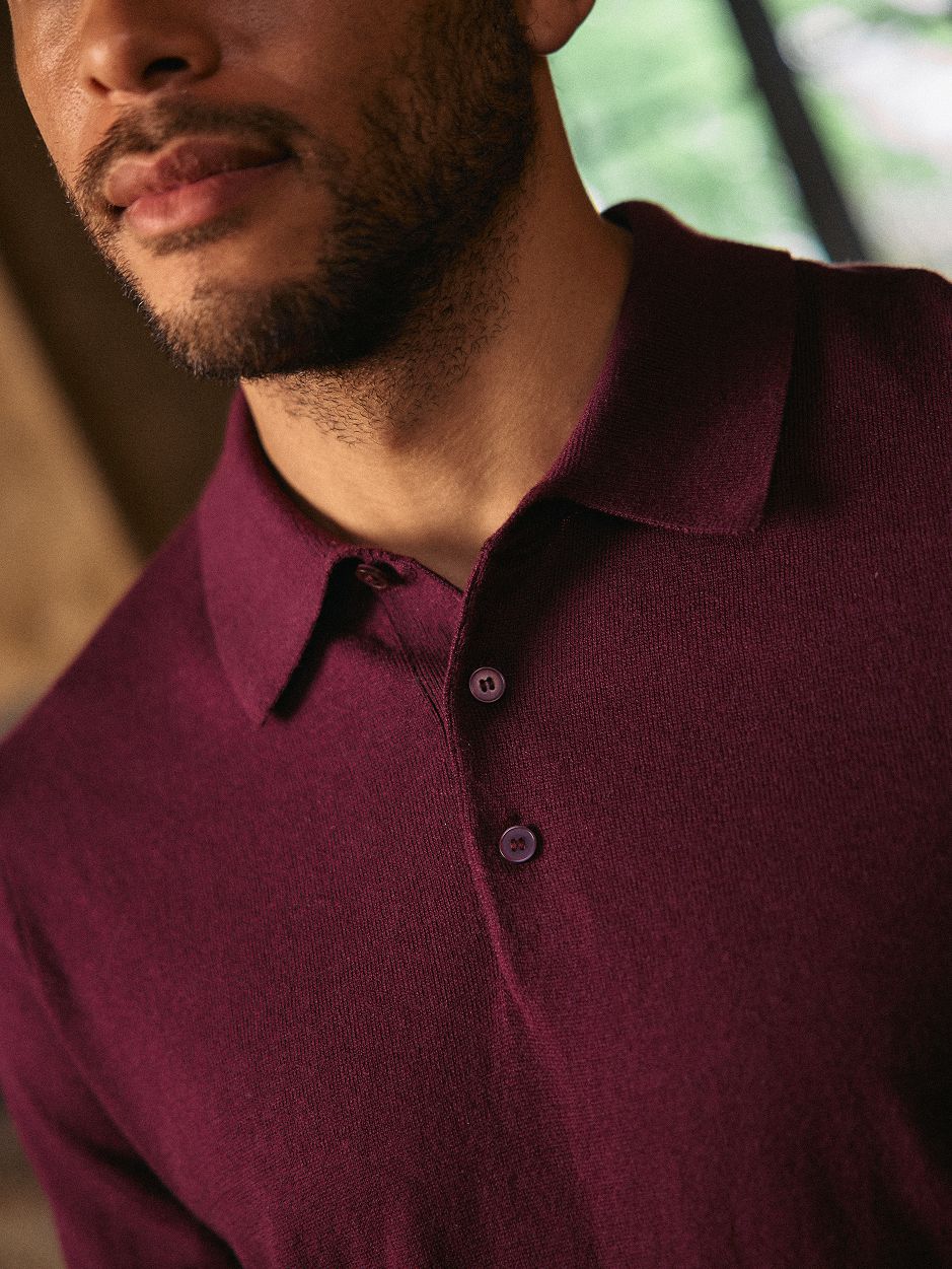 A close-up shot of a man wearing a deep burgundy knit polo shirt.