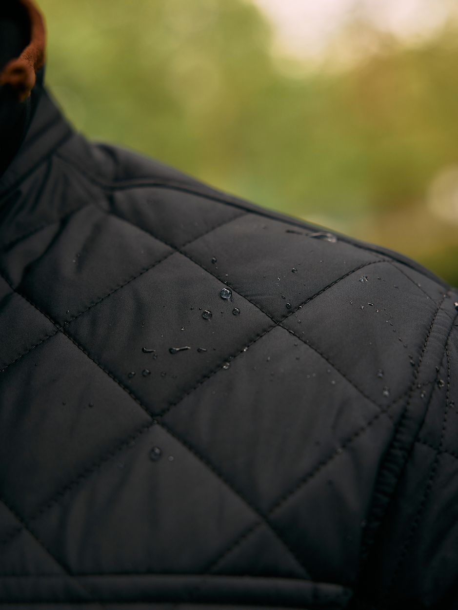 A close-up shot showing water droplets on the shoulder of a black quilted jacket.