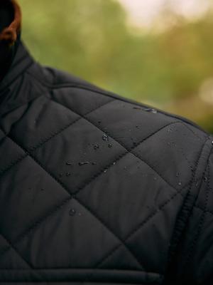 A close-up shot showing water droplets on the shoulder of a black quilted jacket.