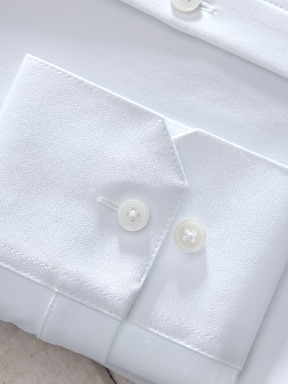 A macro close-up shot of the cuff and buttons on a crisp white dress shirt.