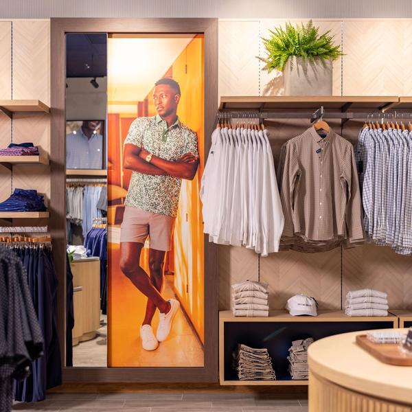 Hanging dress shirts beside a lifestyle photo mural in the Mizzen+Main West Village store
