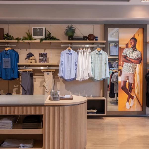 Dress shirts hanging beside a lifestyle photo mural in the Mizzen+Main Southlake Town Square store