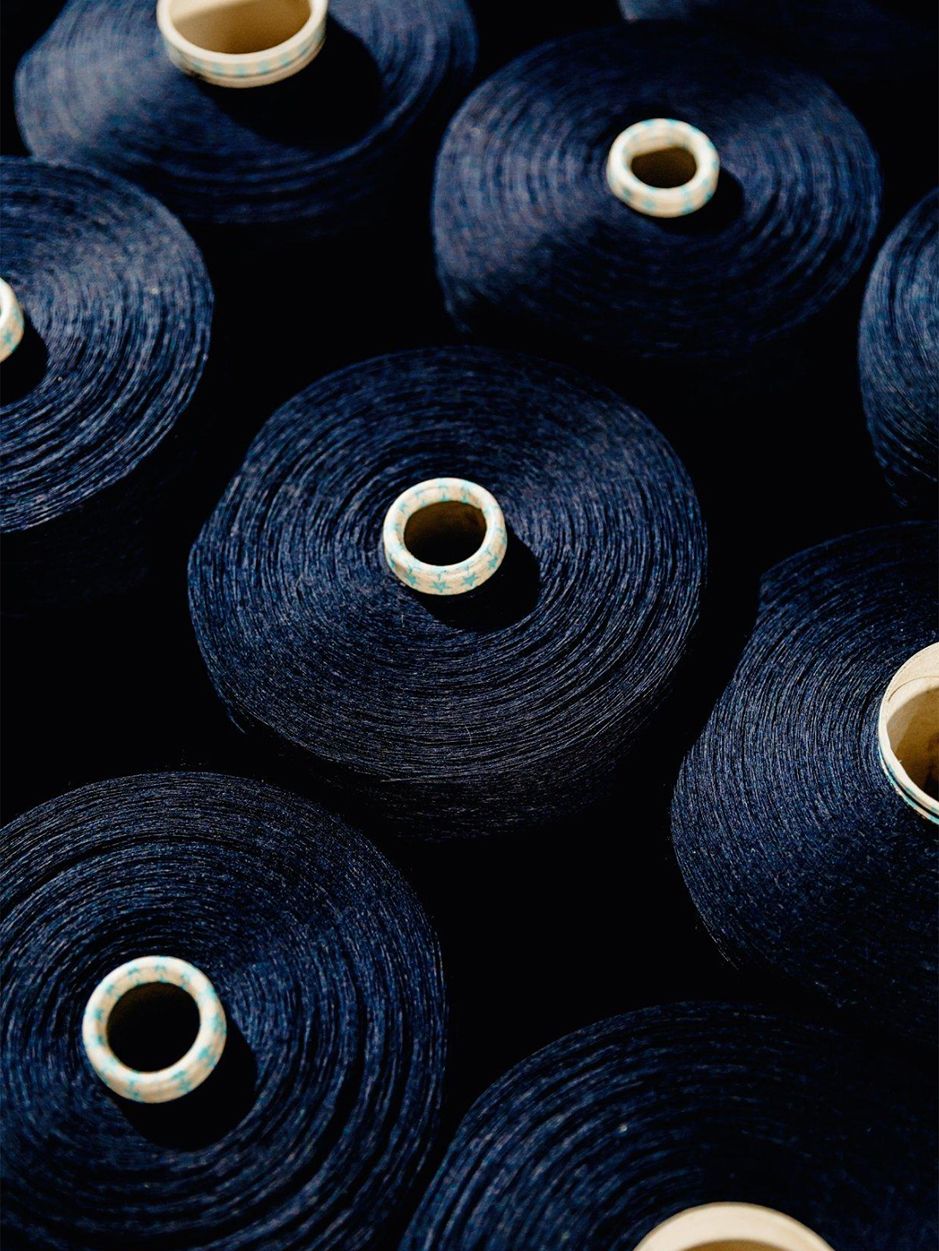 High-angle shot of multiple spools of dark navy blue thread neatly arranged together.