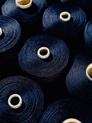 High-angle shot of multiple spools of dark navy blue thread neatly arranged together.