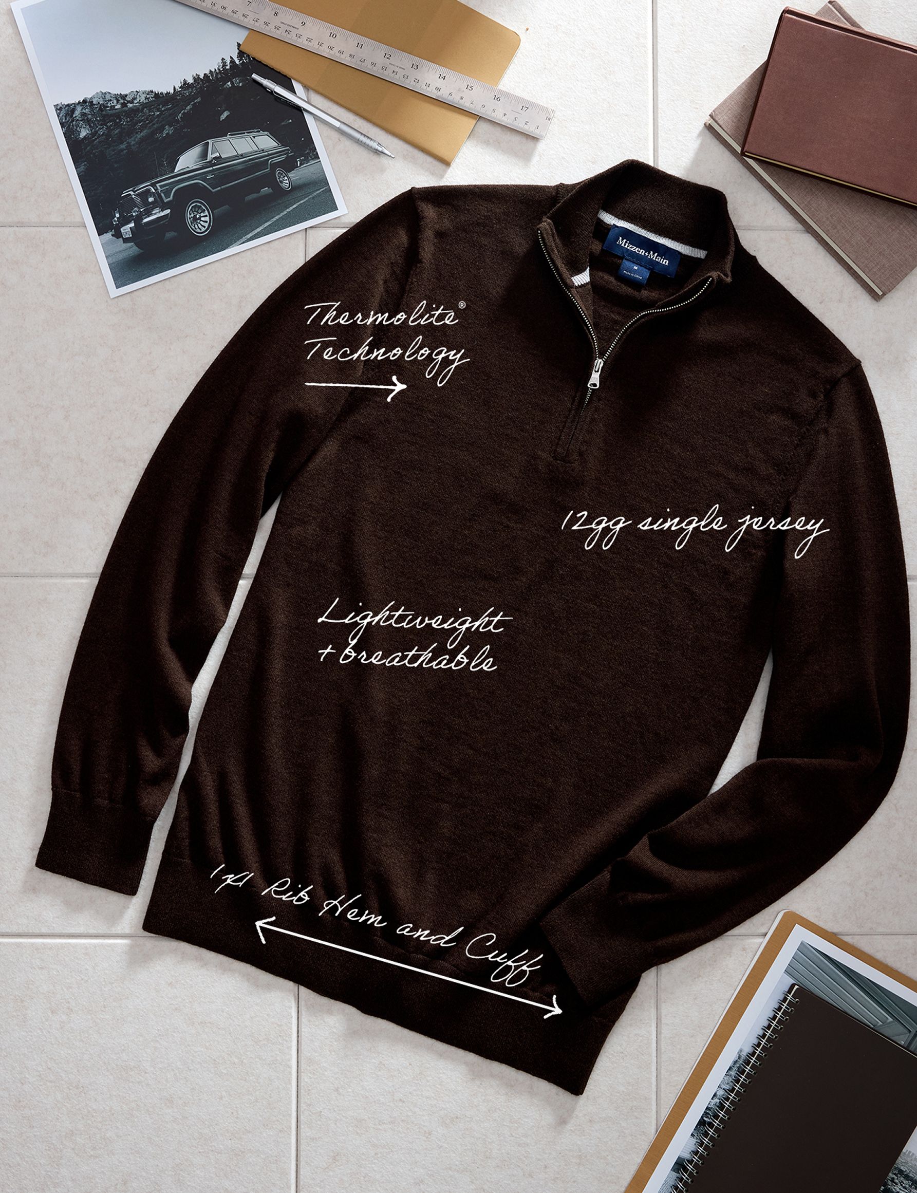 A flat-lay product image of a dark brown quarter-zip sweater with handwritten callout annotations detailing features like Thermolite Technology and Rib Hem and Cuff.