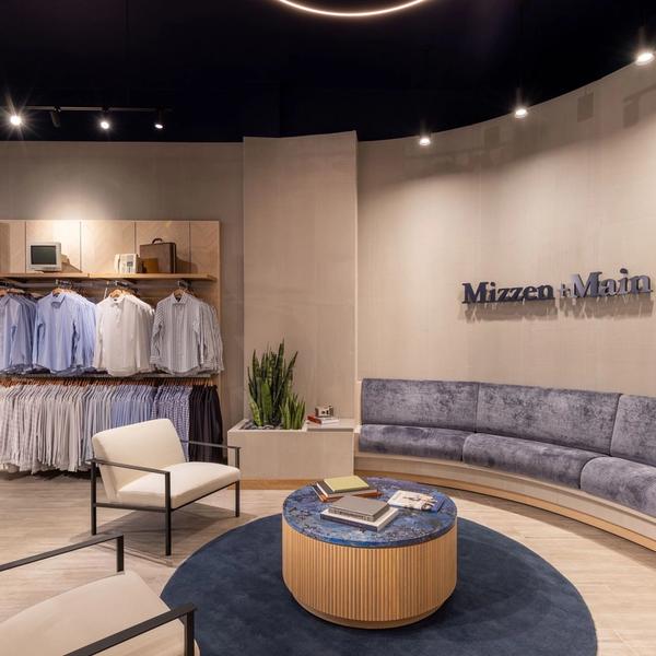 Seating area with a gray velvet banquette and Mizzen+Main sign in the West Village store