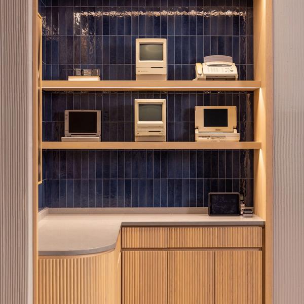 Vintage computers displayed on shelves against navy tile in the Mizzen+Main West Village store