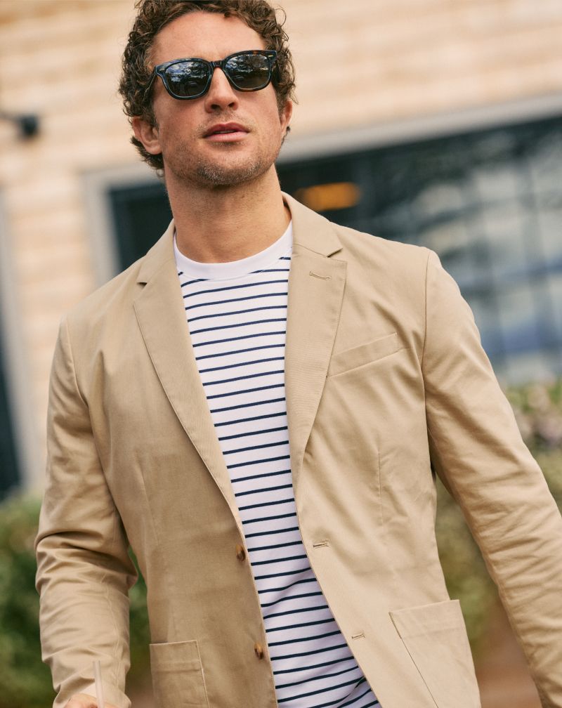 Man in sunglasses wearing a tan Prescott blazer over a navy striped tee