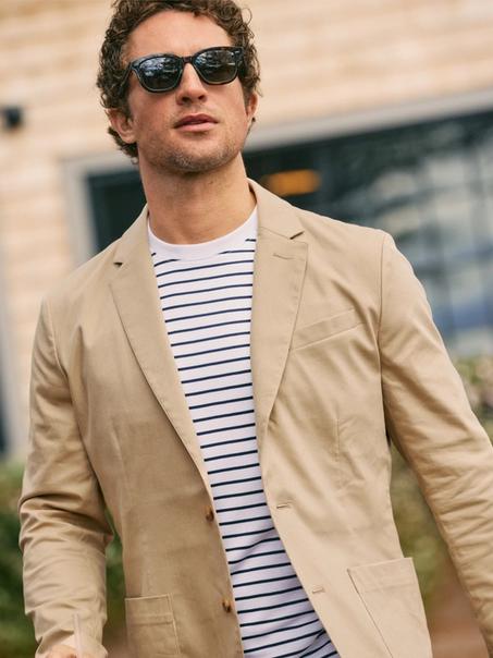 Man in sunglasses wearing a tan Prescott blazer over a navy striped tee