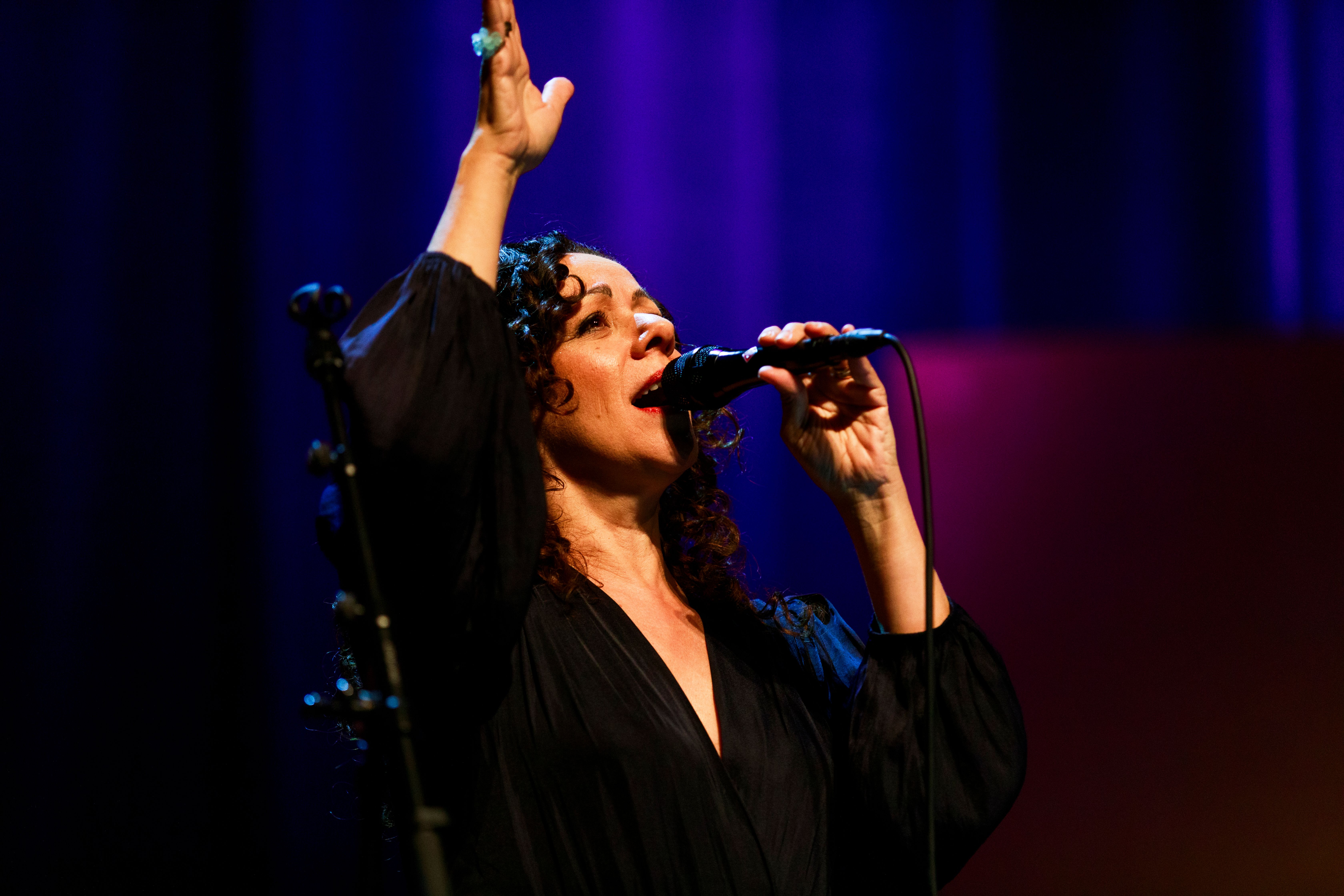 Luciana Souza står med handen i luften och sjunger.