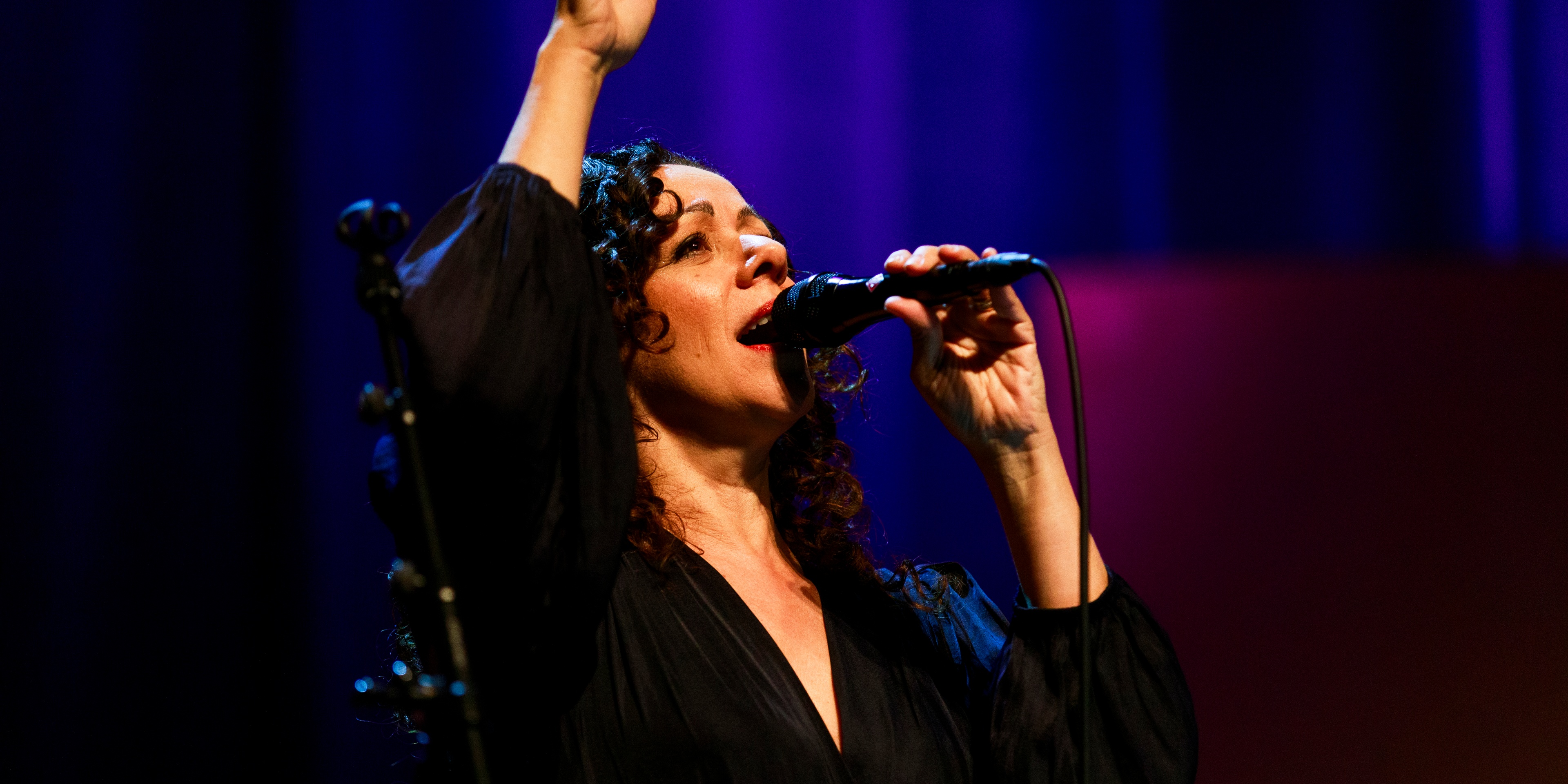 Luciana Souza står med handen i luften och sjunger.