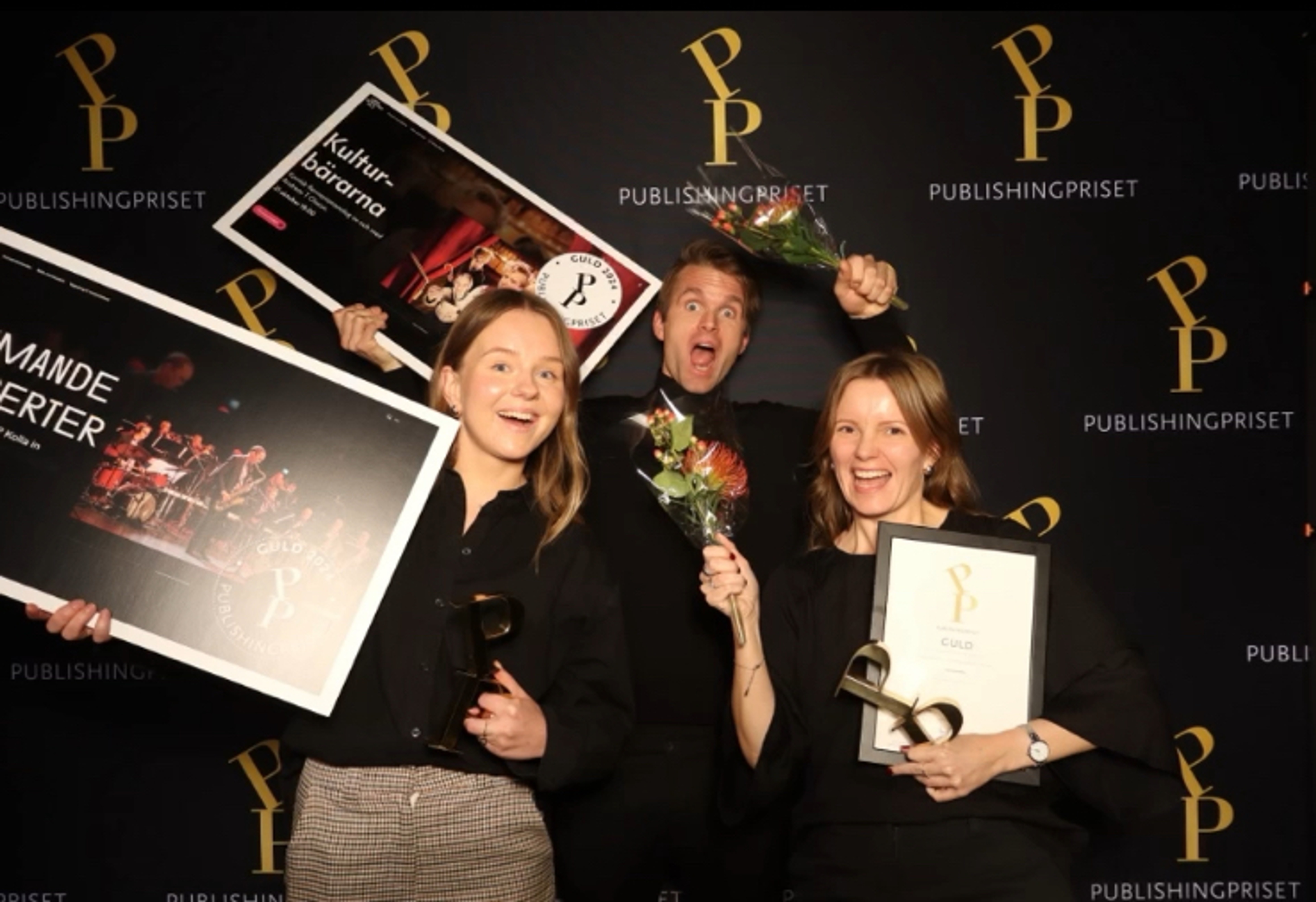 Tre glada personer som håller i diplom och statyetter.