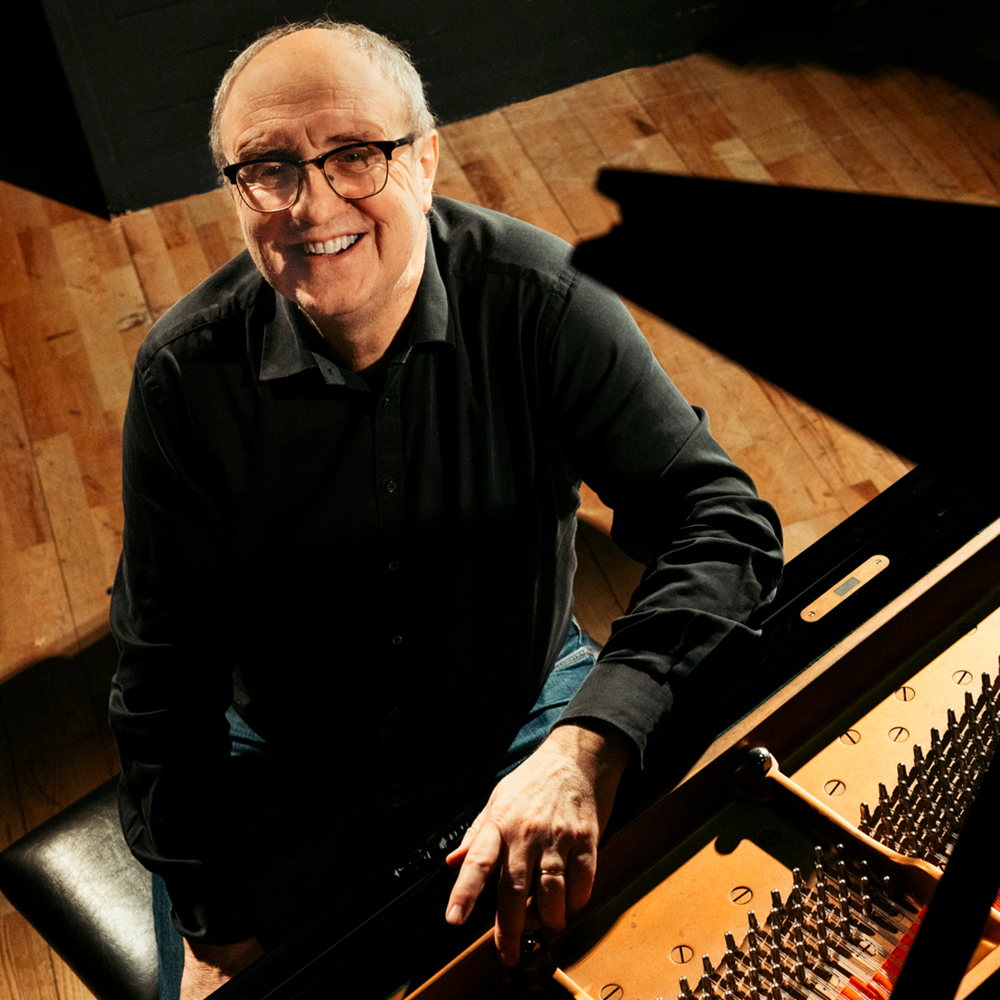 Pianisten Lars Jansson sitter vid en flygel.