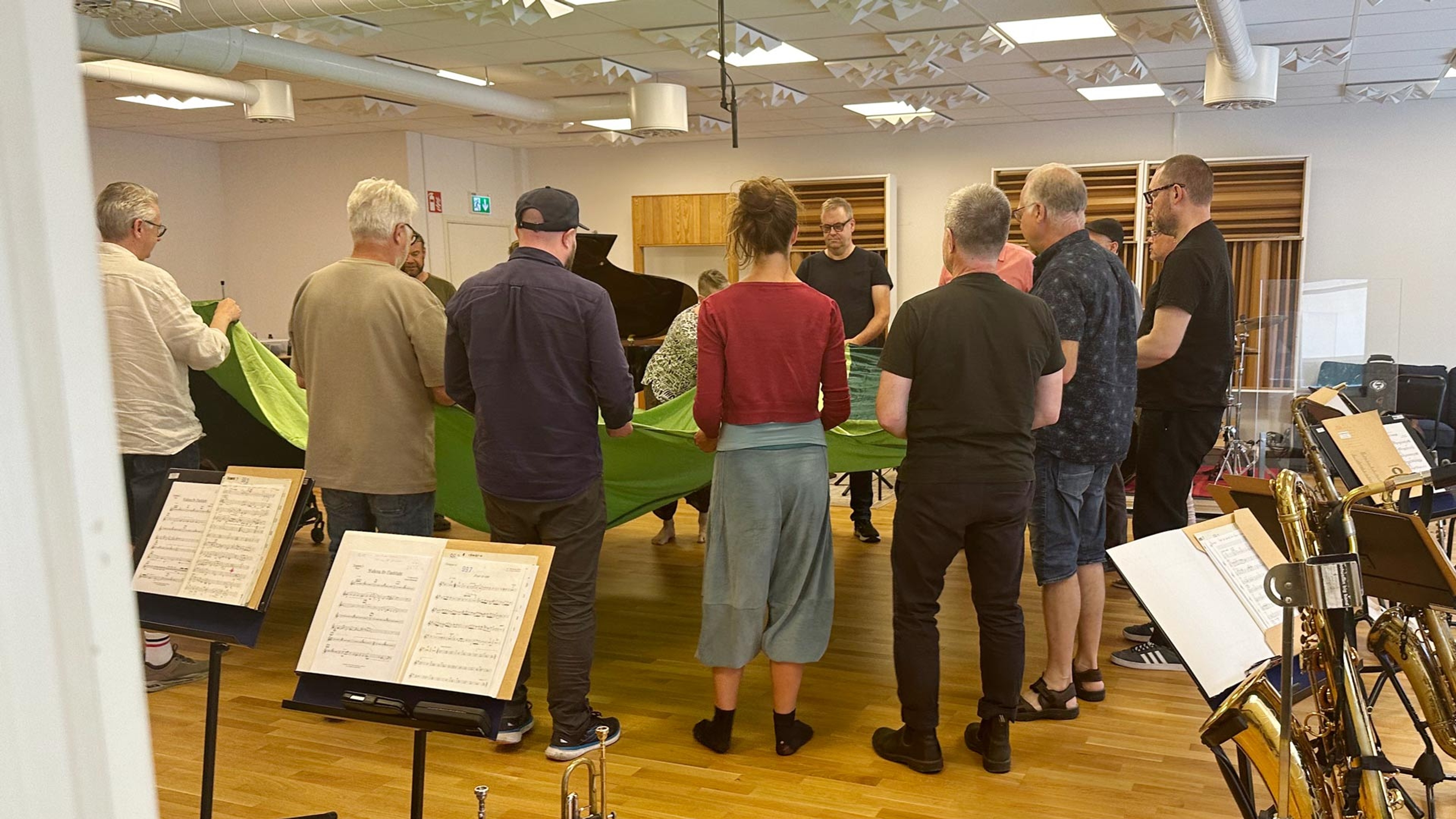 Musikerna står och håller i ett stort grönt tygstycke.