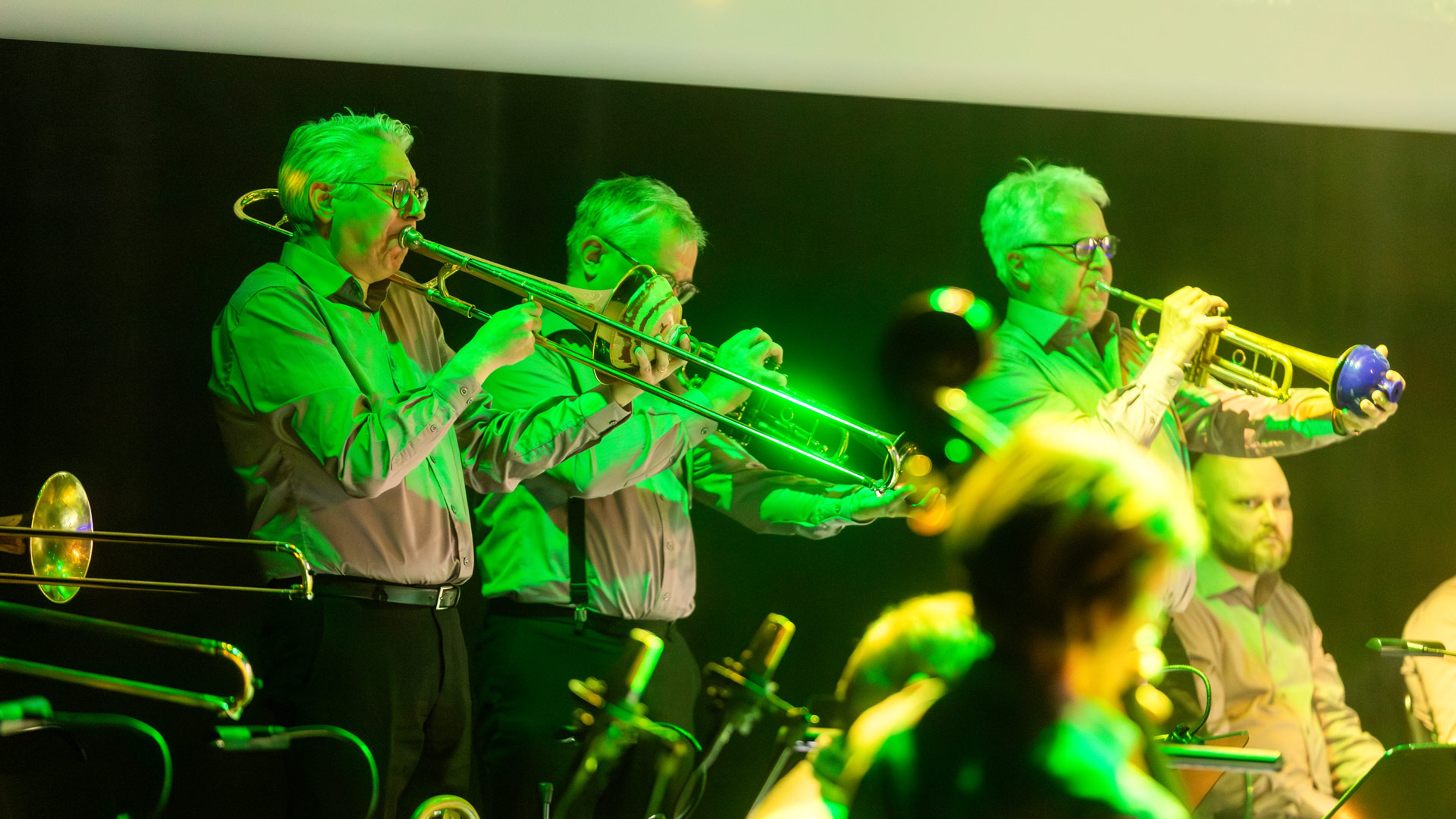 Två trumpetare och en trombonist spelar musik.