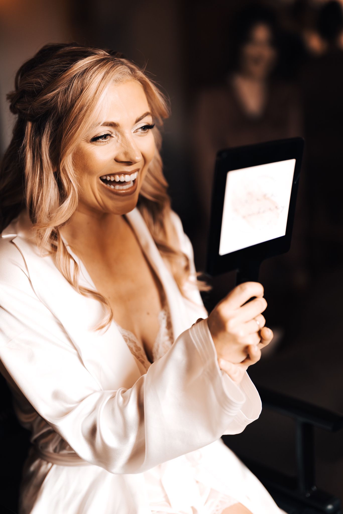 bride looking at he self in the mirror in white dressing gown