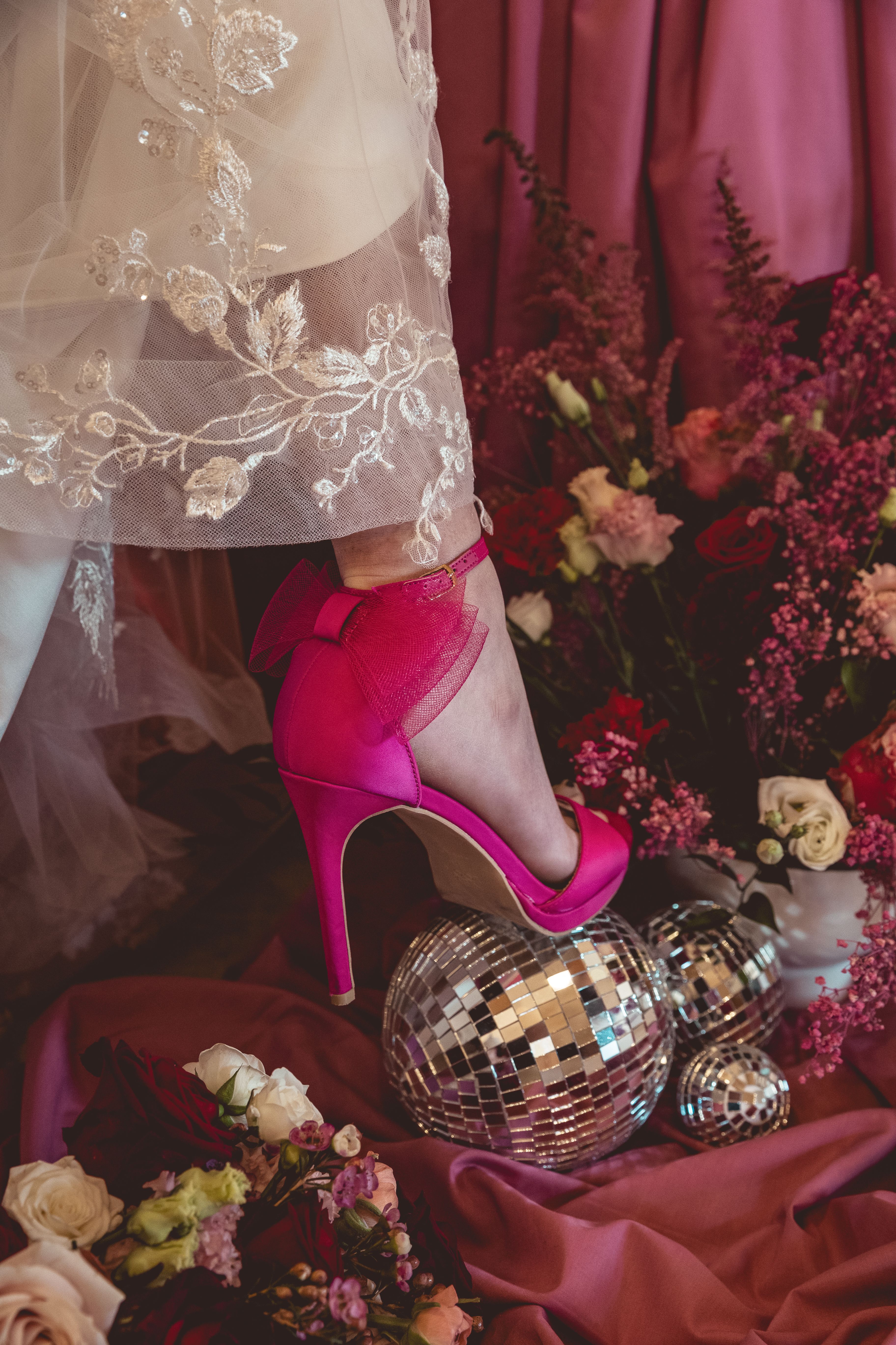 pink shoe with bow on disco ball and flowers in wedding dress