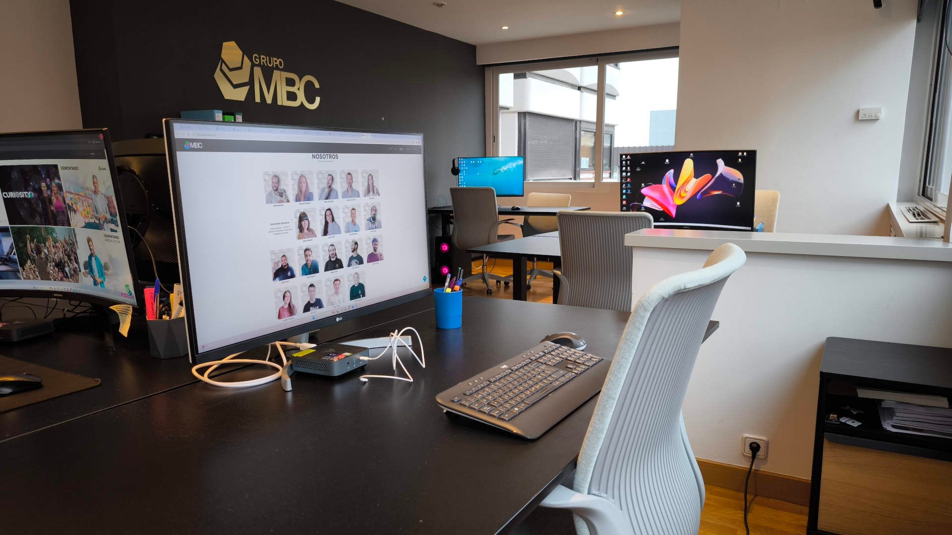 Puesto de trabajo con monitores y logotipo de Grupo MBC