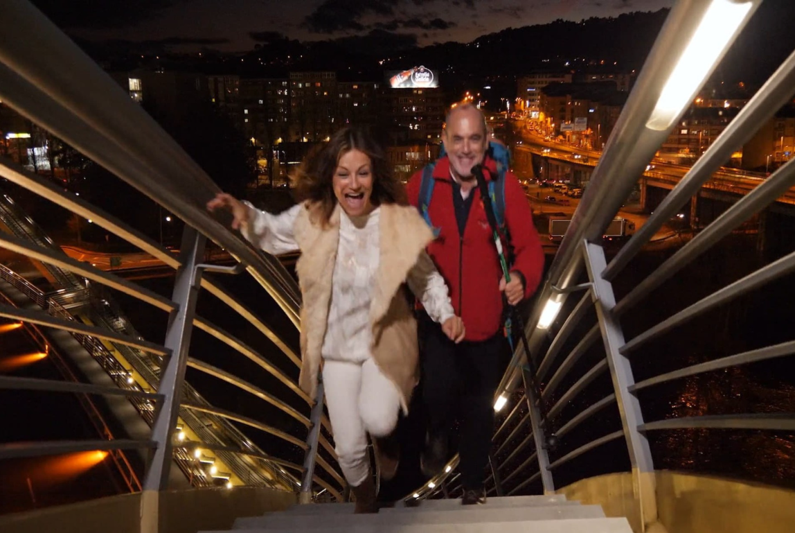 Escena nocturna del spot Ourense, corazón do Camiño, con dos protagonistas subiendo las escaleras de una pasarela mientras recorren la ciudad de Ourense. 