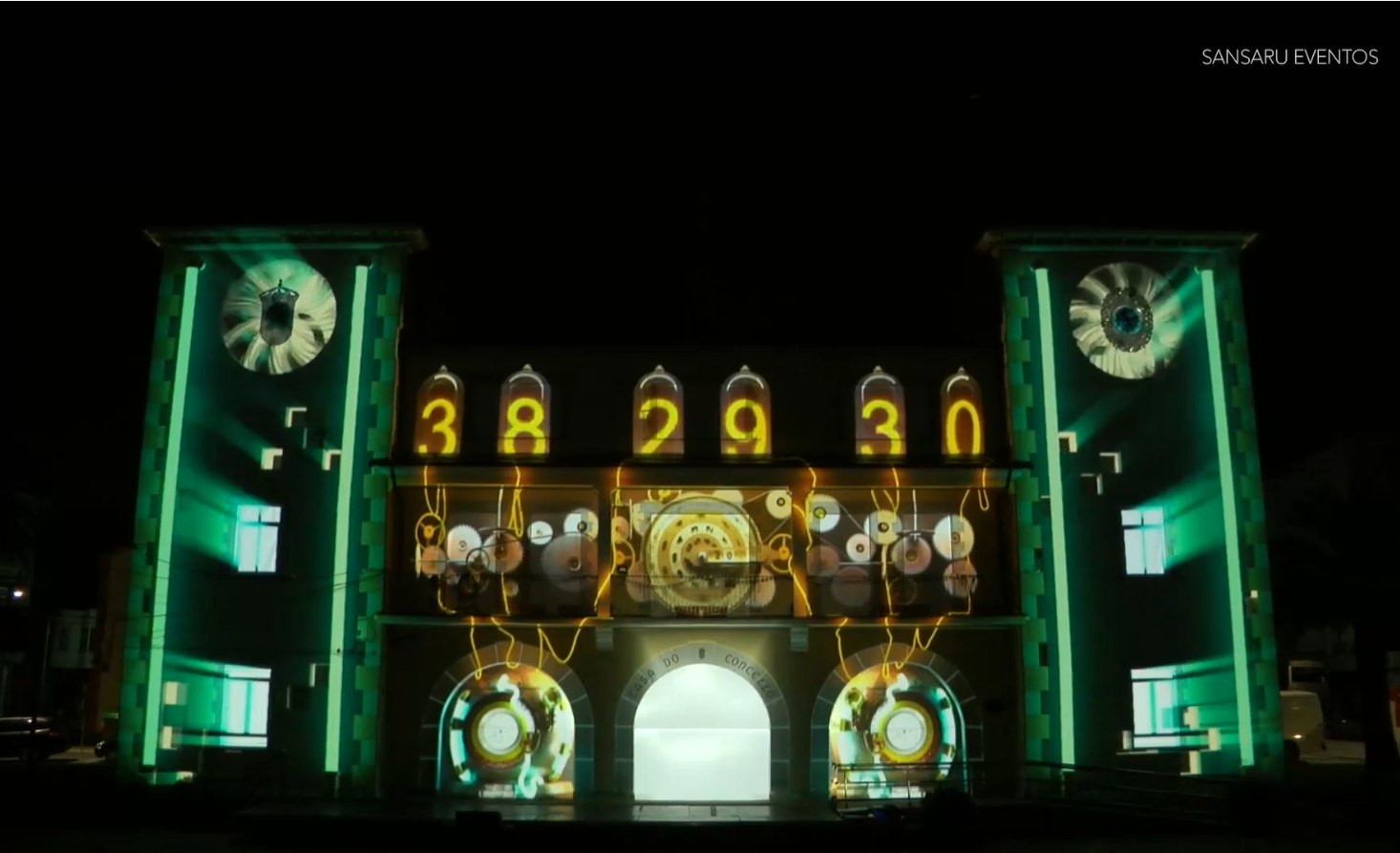 Proyección de videomapping sobre la fachada de la Casa do Concello de As Pontes durante el espectáculo Contigo, avó, con engranajes, números y elementos gráficos integrados en la arquitectura.