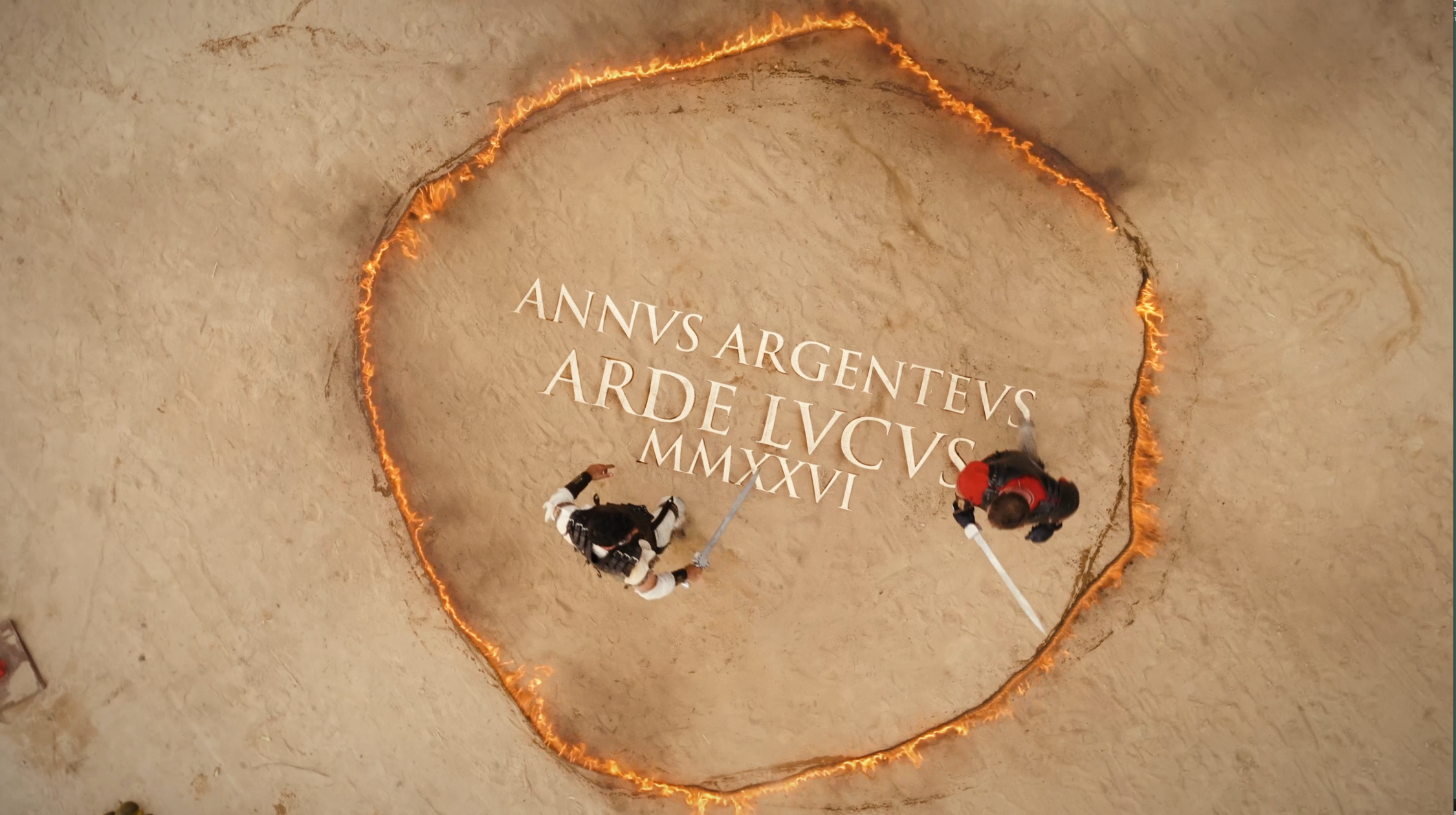 Vista cenital del spot de Arde Lucus 2026, con dos guerreros enfrentándose con espadas dentro de un círculo de fuego sobre la arena.