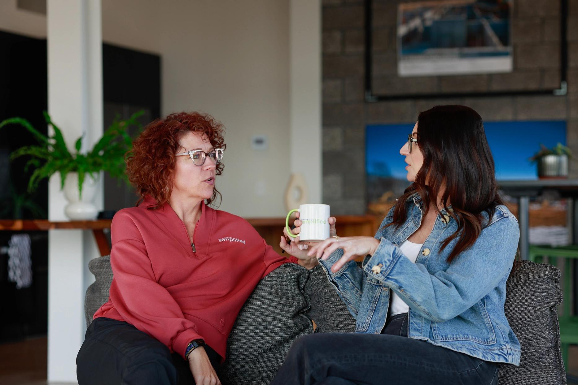 Two team members discussing on couch over coffee