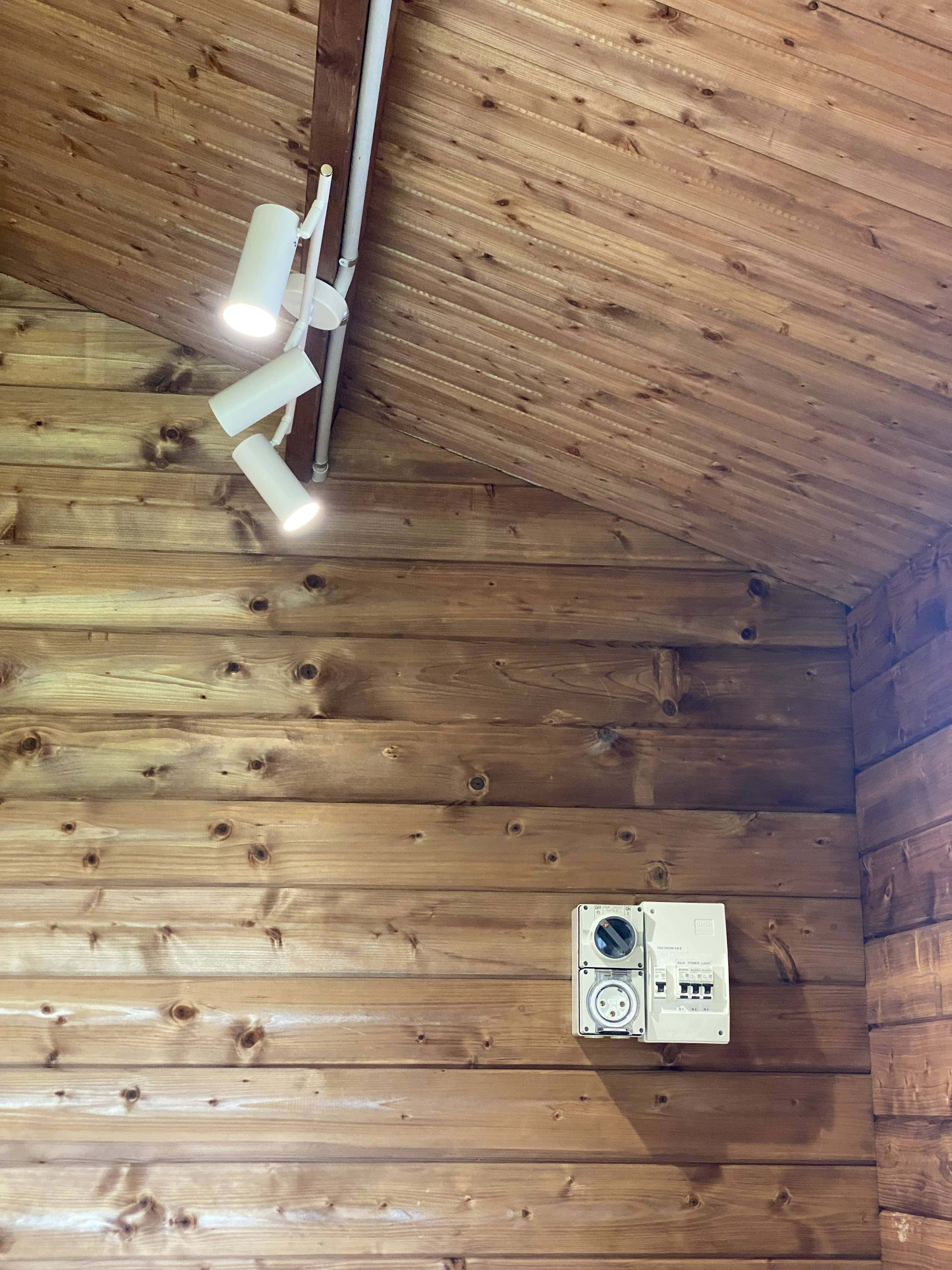 Closeup of track lights and power board on timber studio wall