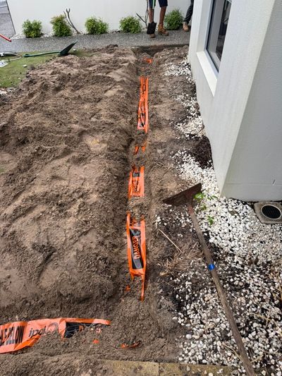 Orange electrical warning tape over a buried feed beside the house at Mossman Court