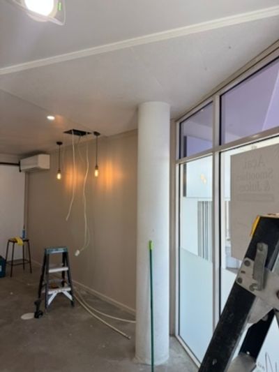 Pendant drops beside a column and shopfront glass during the Good Eats seating fit-out