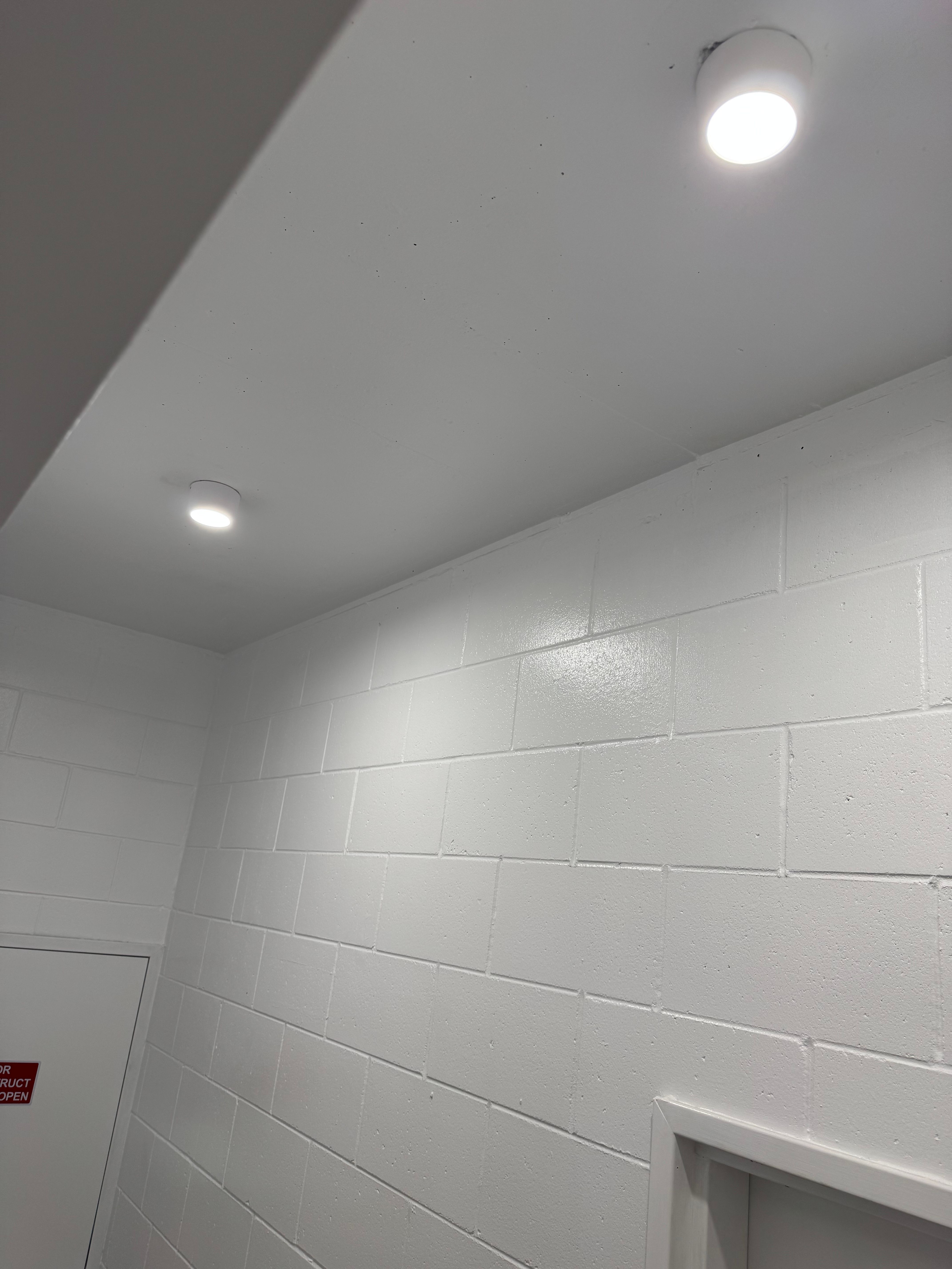 LED ceiling downlight in white-painted brick hallway