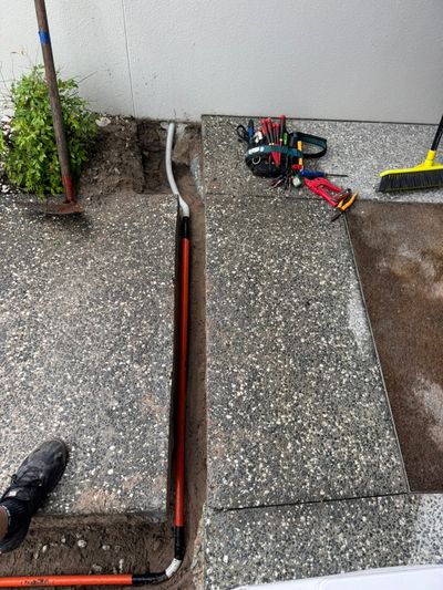 Orange conduit crossing a paved path in an open trench at Mossman Court