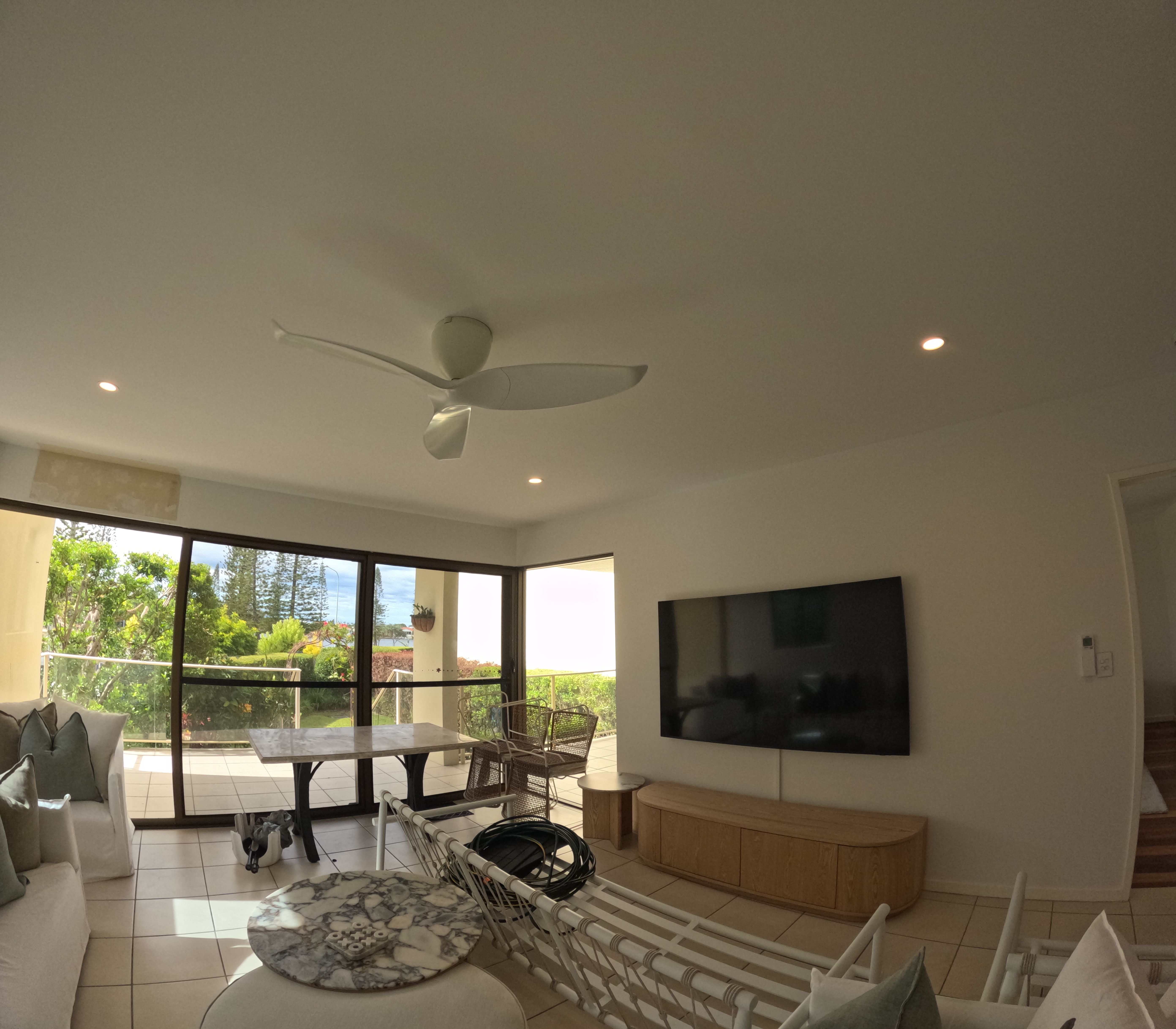 Modern ceiling fan, downlights, and wall-mounted TV in lounge