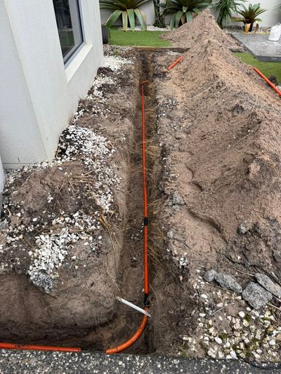 Orange underground conduit in an open trench along the house at Mossman Court