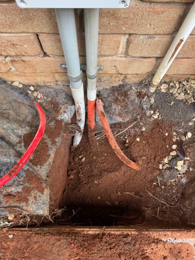 New conduits dropping from a wall box into a trench at the Palmwoods house