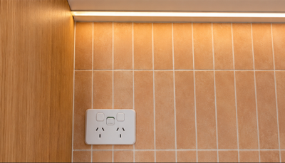 Modern double power point installed neatly against tiled kitchen splashback with concealed LED strip lighting above.