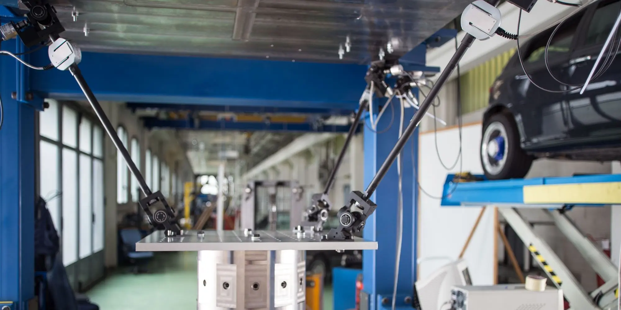 Apparato di laboratorio con telecamere e bracci sensorizzati che inquadrano una piattaforma metallica per prove meccaniche.