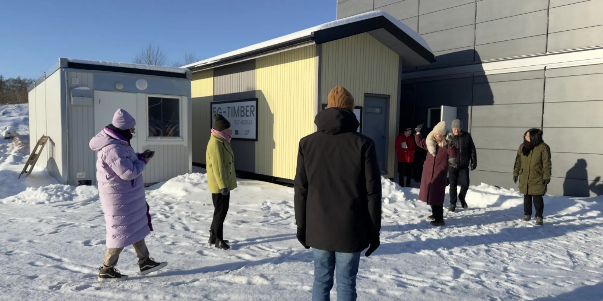 People outside the 5G-TIMBER experimental modules in a snowy area.