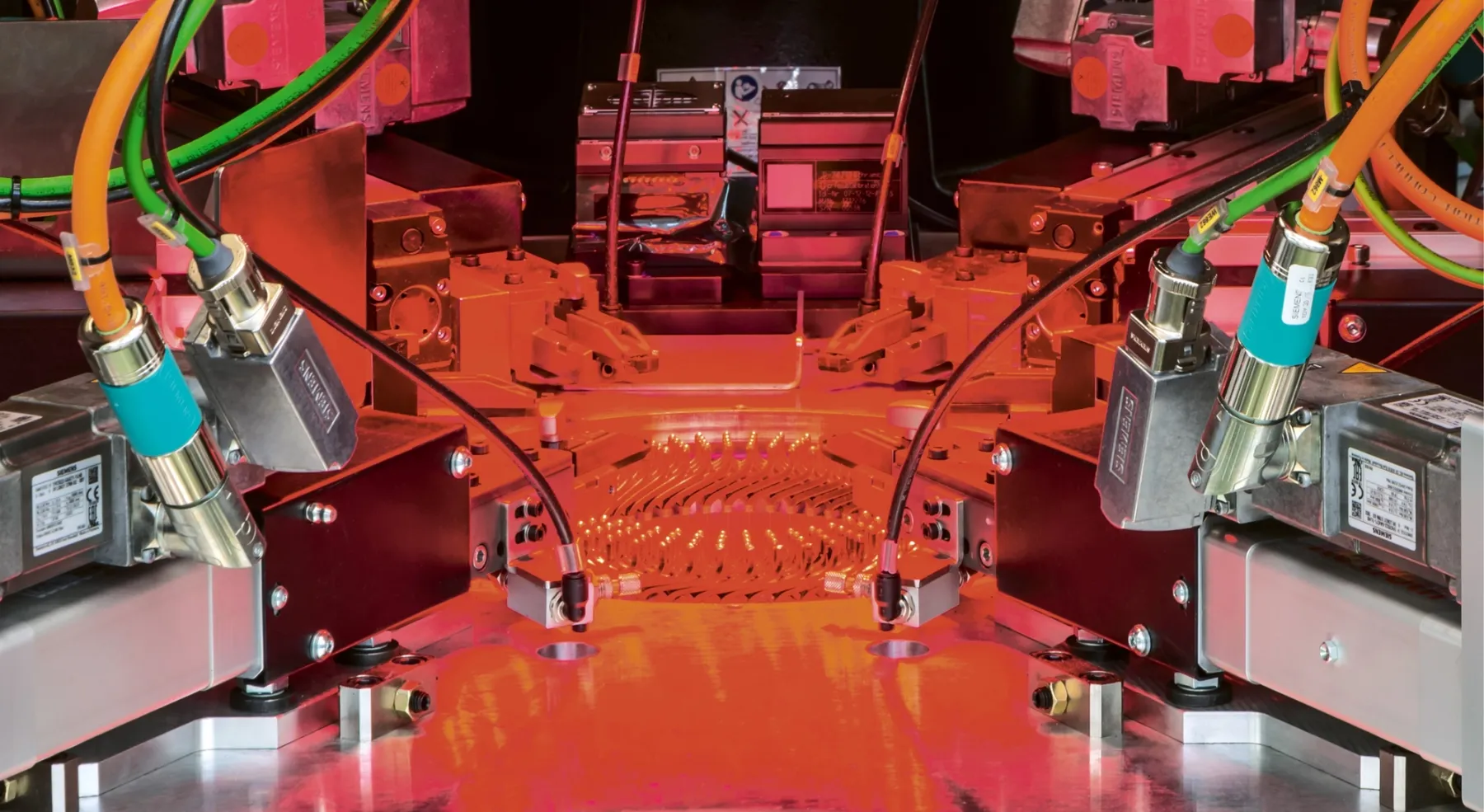 Sistema industriale automatizzato con sensori, cavi e componenti elettronici illuminati da luce rossa.