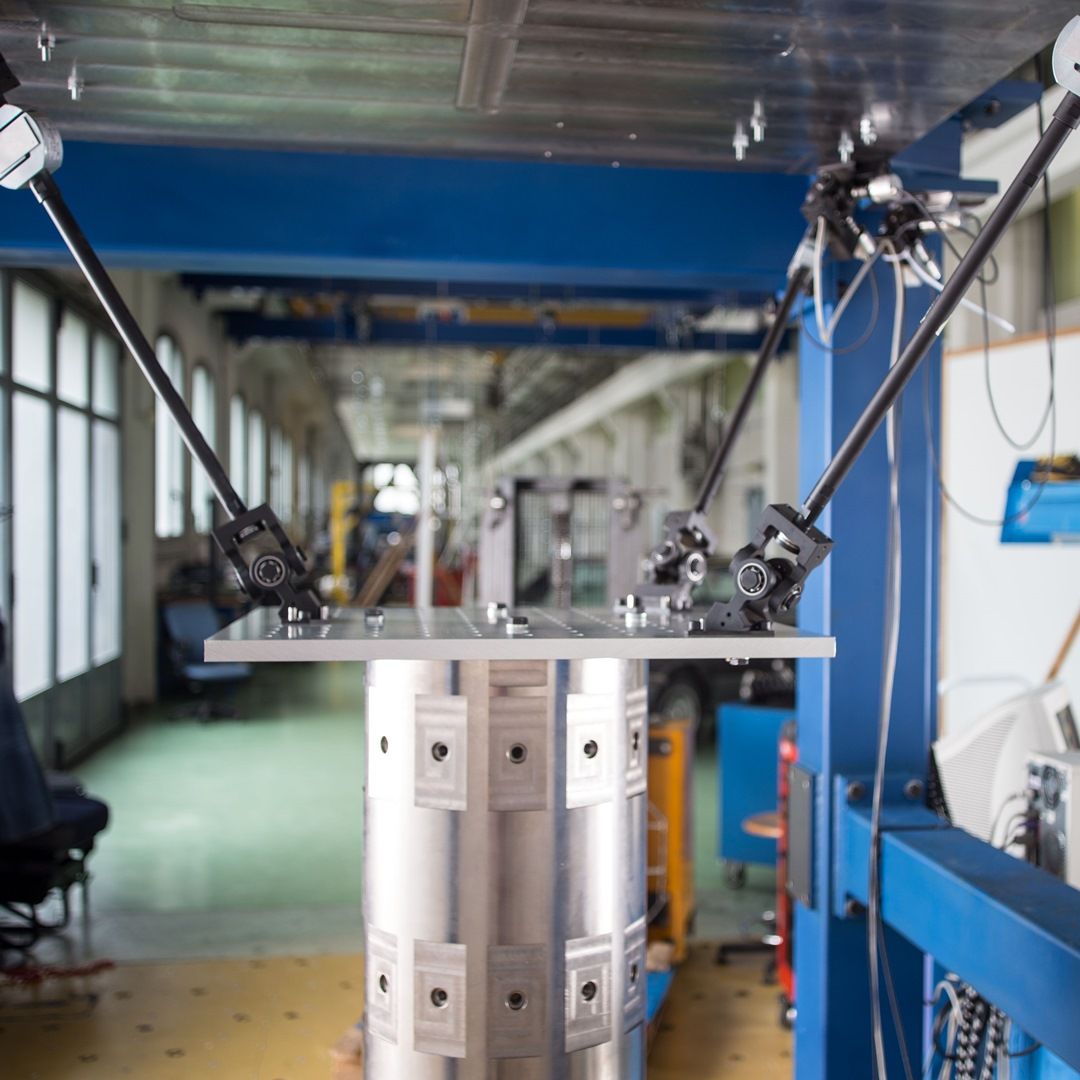 Metal platform monitored by several cameras mounted on rigid arms in a mechanical testing laboratory.