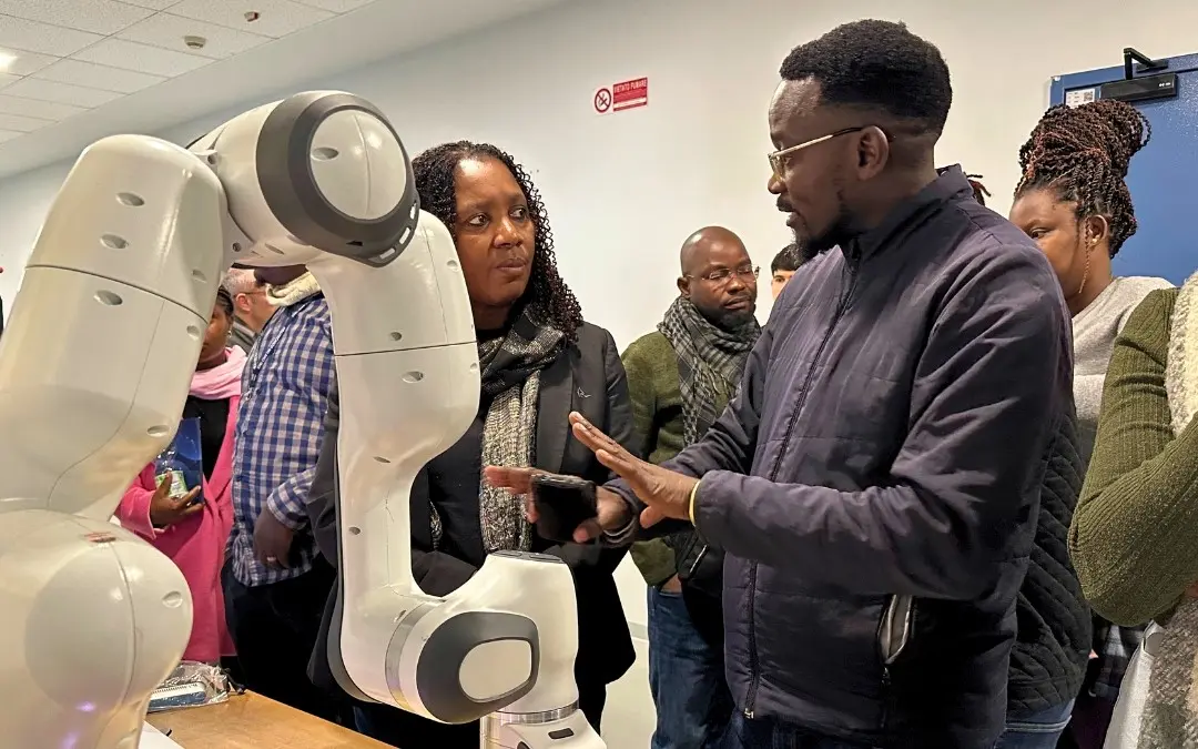 People observing and discussing a collaborative robotic arm during a demonstration.