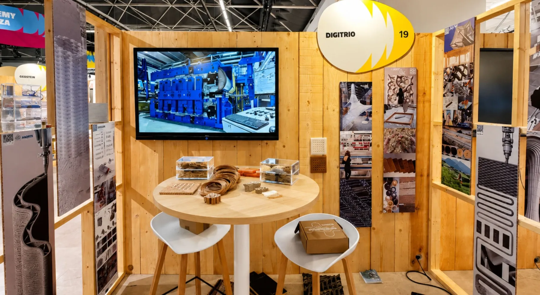 Stand del progetto DIGITRIO con pannelli informativi, monitor e campioni di materiali.