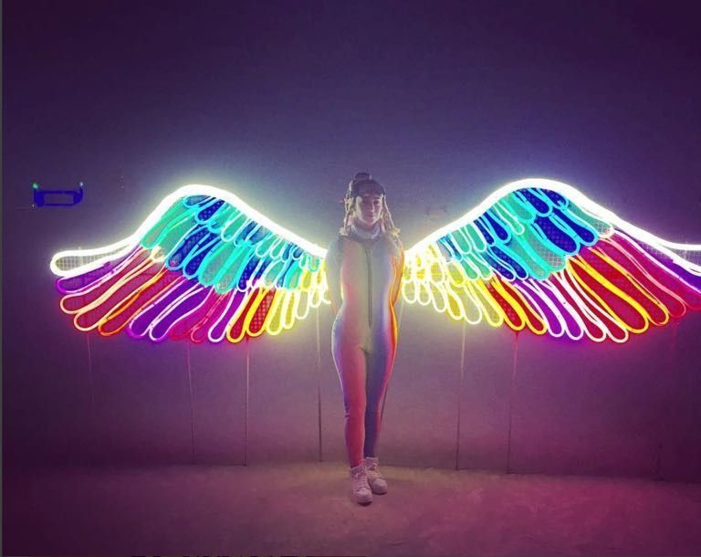 Katy Perry in front of rainbow LED neon wings at Burning Man