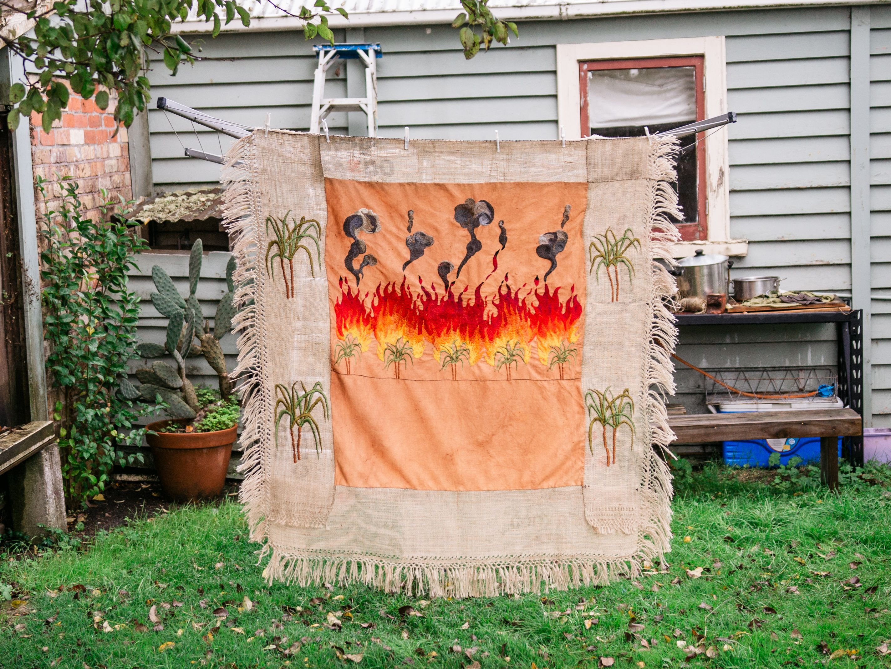 Quishile Charan, Burning Ganna Khet (Burning Sugarcane Farm), 2021, 153cm by 152cm. Technique: hand dyed textile, embroidery thread, cotton, hessian sacks. Textile is naturally dyed with avocado seeds. Image by Matavai Taulangau.