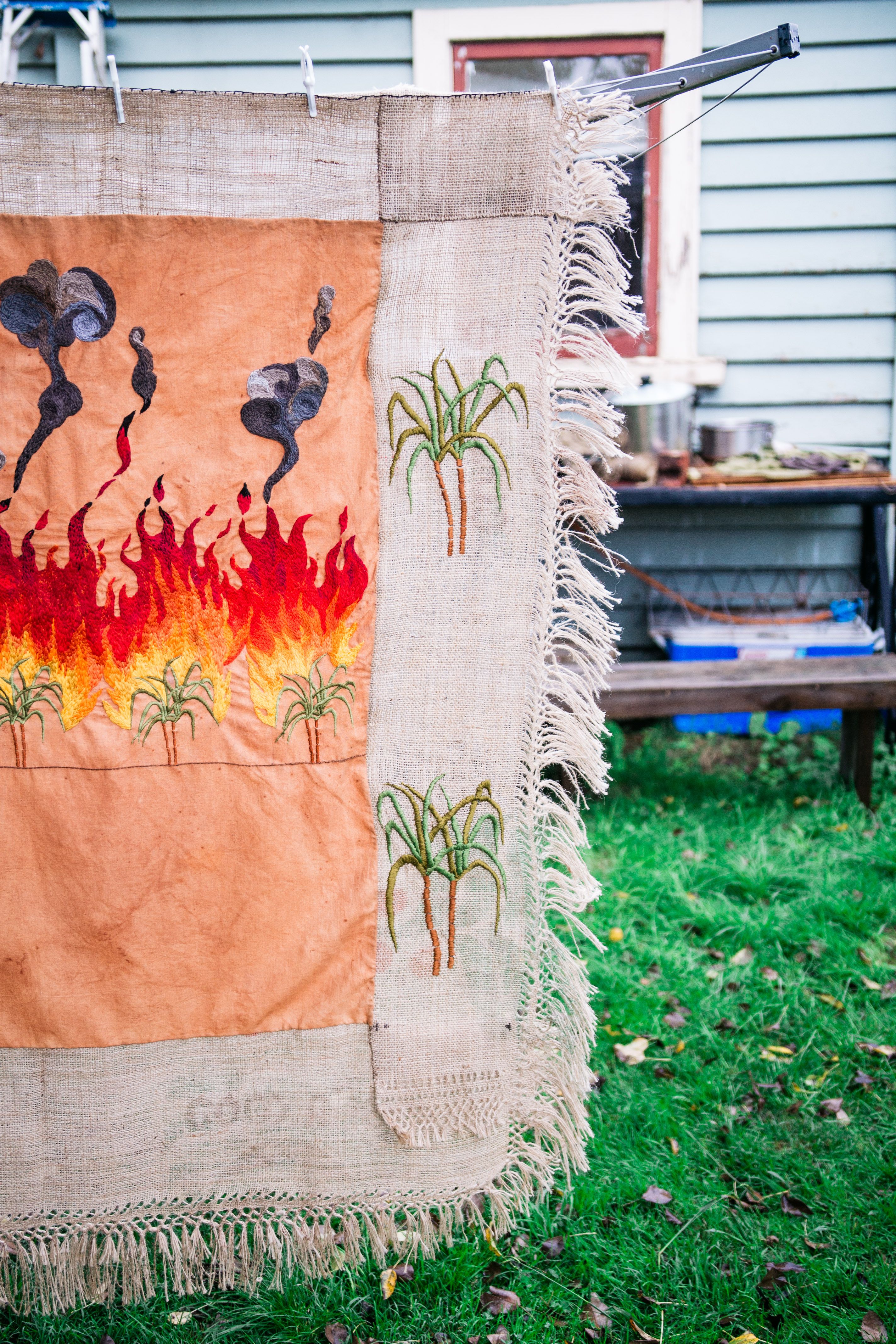 Quishile Charan, Burning Ganna Khet (Burning Sugarcane Farm), 2021, 153cm by 152cm. Technique: hand dyed textile, embroidery thread, cotton, hessian sacks. Textile is naturally dyed with avocado seeds. Image by Matavai Taulangau.