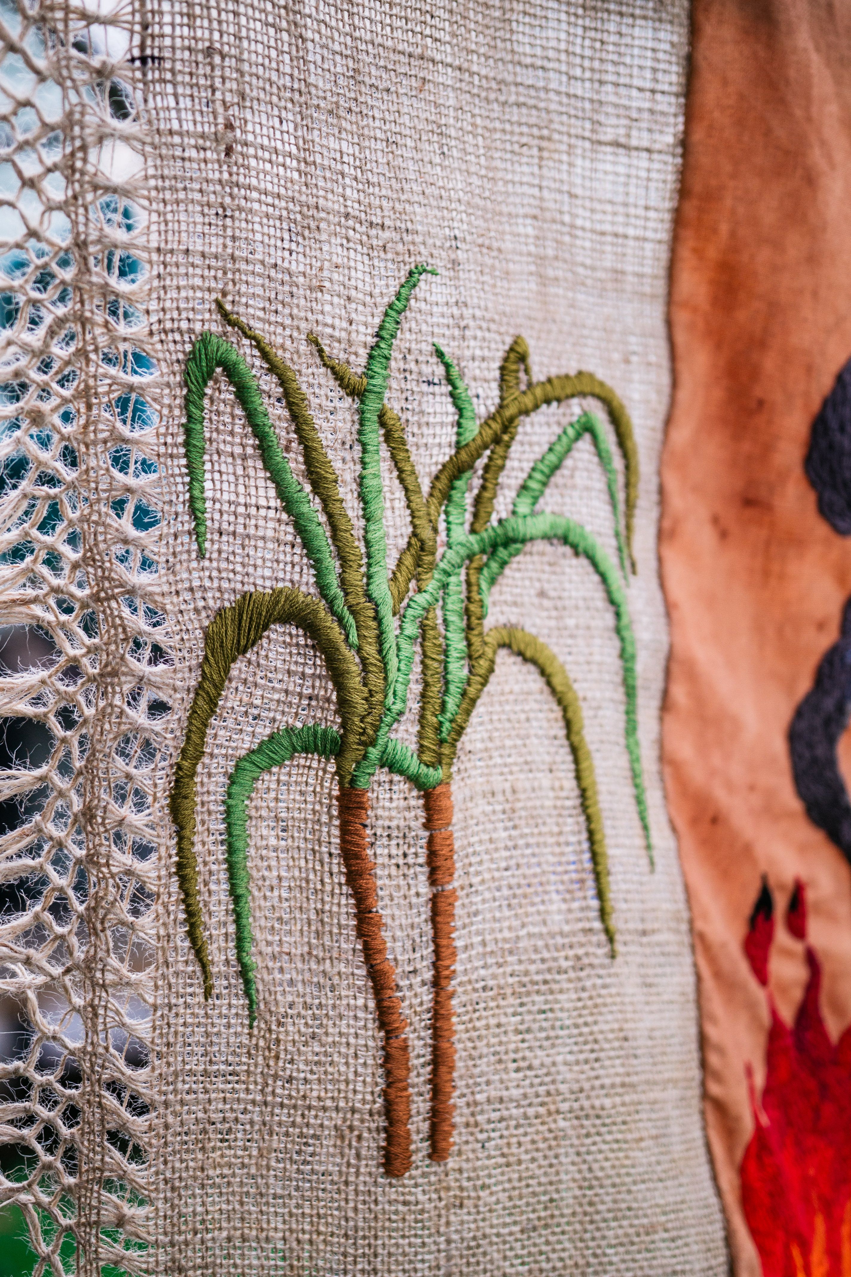 Quishile Charan, Burning Ganna Khet, 2021, cotton, embroidery thread, hessian sacks, natural dye: avocados, 153cm by 152cm. Close up of embroidery. Image taken by: Matavai Taulangau.