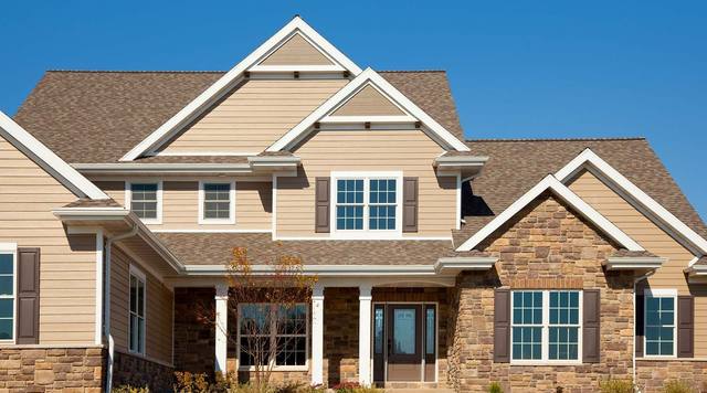 Two-story craftsman home with stone wainscot and tan lap siding, from Sherwin-Williams’ exterior color gallery