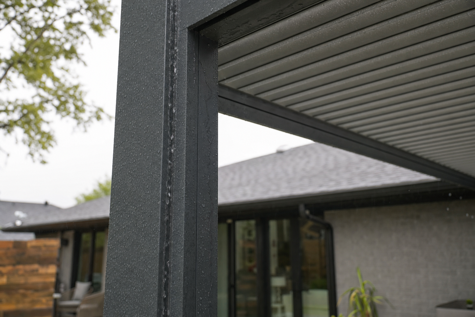 Closed aluminum louvered pergola shedding rain through hidden drainage channels in posts